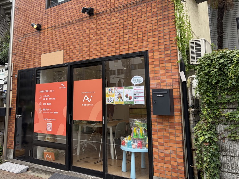 エゼット不動産の店頭。ガラス窓に、ロゴとサービスの案内が貼られている